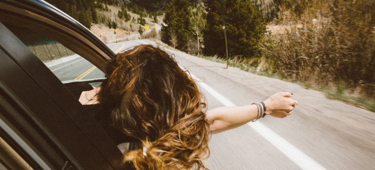 a woman enjoying a road with her head out of the car's window