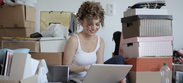 woman sitting on a floor with a laptop surrounded by boxes, waiting for long distance movers DC