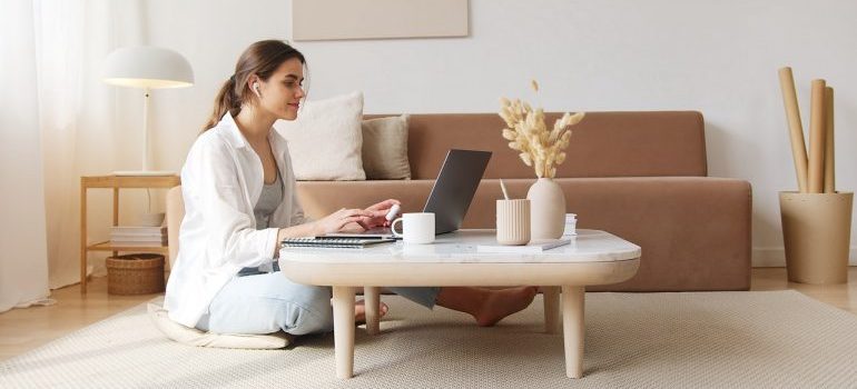 A smiling woman using laptop to find the best storage services DC area can offer.