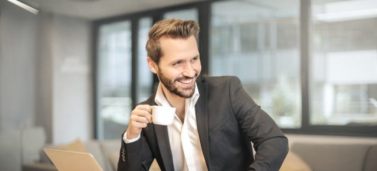 A smiling businessman holding white teacup.