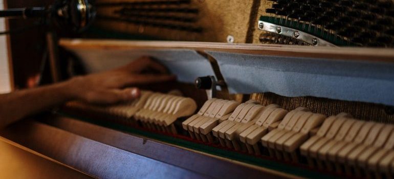 A hand touching the piano's internal sound mechanism