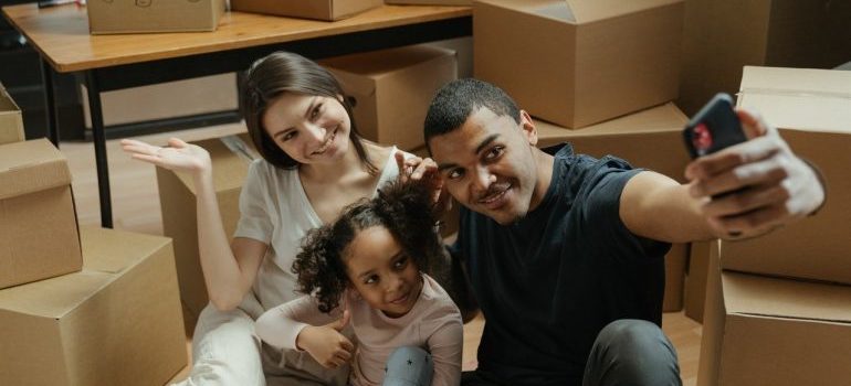 A happy family taking a selfie among moving boxes while waiting for local movers MD