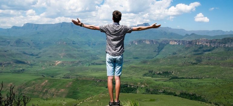 A man standing on a hilltop with arms spread.