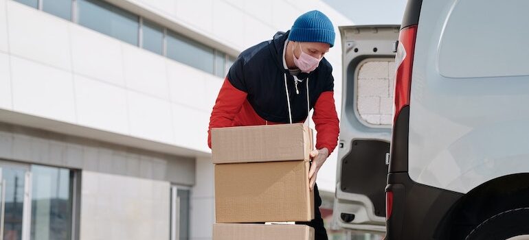 A man in a red and black hoodie loading boxes into a van.