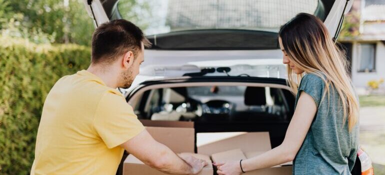 A man and a woman putting boxes in a car before hiring movers Bethesda MD has.