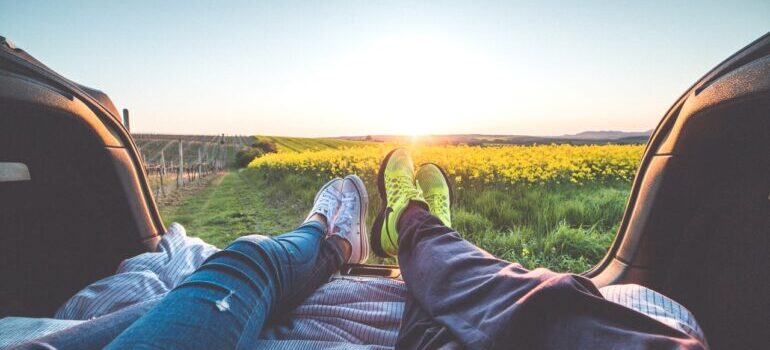 Two pair of feet with flower field in the background.