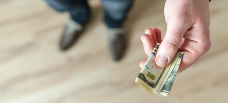 a man holding a dollar bill and calculating moving costs