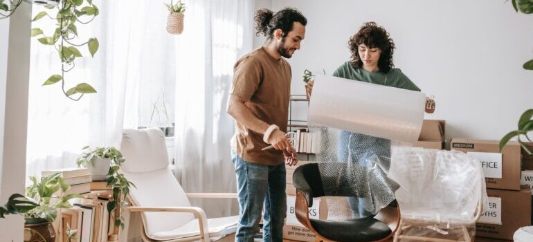 Man and woman usin bubble wrap to wrap the chair