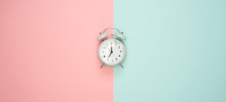 An alarm clock on a pink and blue surface.