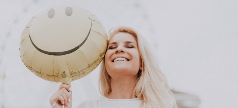 Woman smiling and holding a smiley baloon