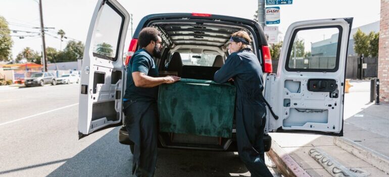 Men loading up the van with furniture.