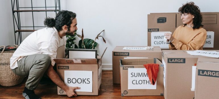 a man picking up a box from the floor as the woman watches him