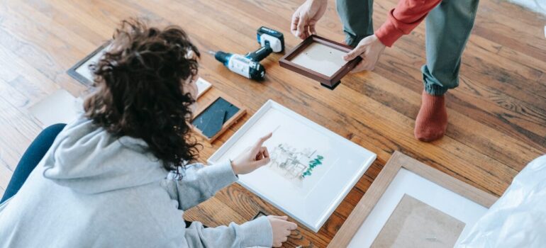 a woman sitting on the floor deciding what picture is worth packing