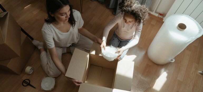 a mother packing items with her child using bubble wrap