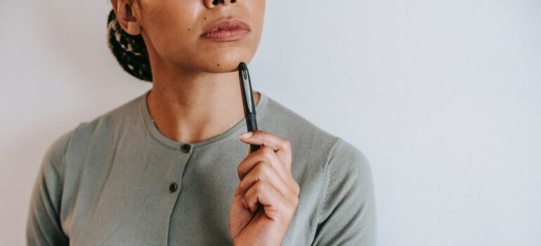 A woman thinking with a pen