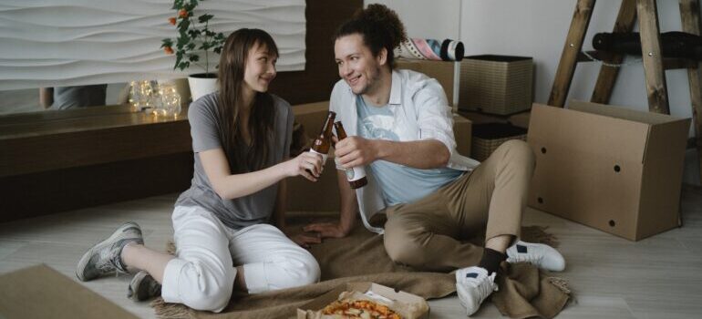 Man and woman eating pizza on the floor.