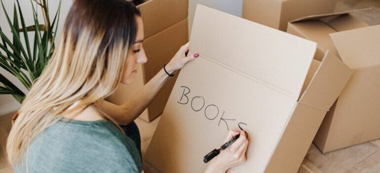 A woman labeling moving as one of tips for packing your book collection for the move