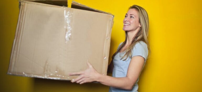 Women holding cardboard moving box