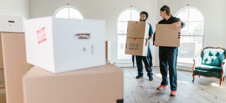 two men woking for a moving company carrying boxes through a home after their client was able to find reliable local movers in Maryland