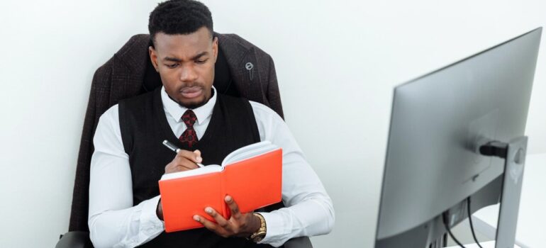 a man in a suit takes notes in front of his PC