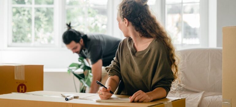 a man carrying a plant while the woman makes a list of items