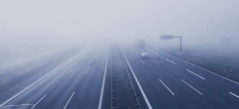 a foggy highway with cars disapearing in the distance
