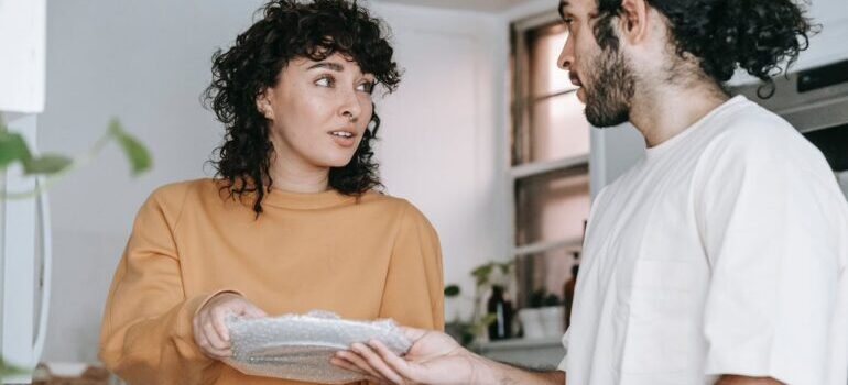 A couple holding plate wrapped in a bubble as a way of packing your kitchen for your DMV move