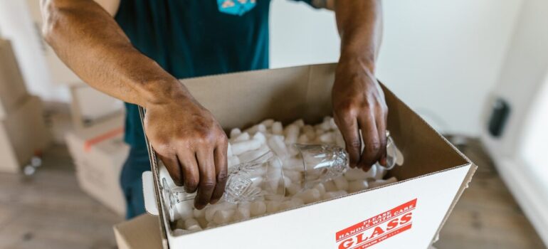 a mover carefully placing glasses inside a box with packing peanuts