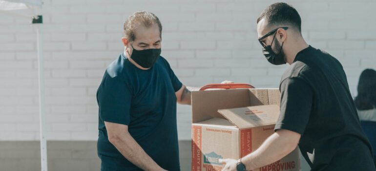 a person donate unwanted items after moving to Washington by handing a cardboard box to another person