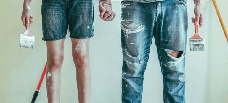 a couple holding hands in the middle of repainting a room