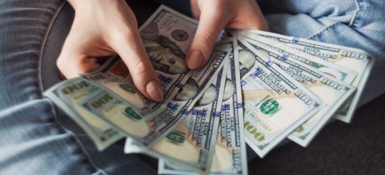 a woman holding a stash of money to represent ways to cut Washington moving expenses