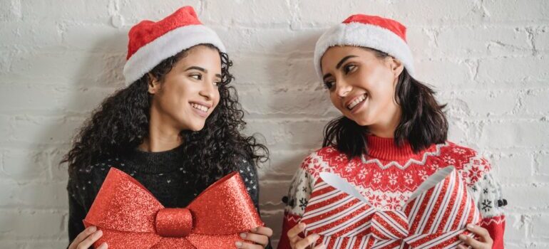 Two girls in Christmas clothes holding big bows