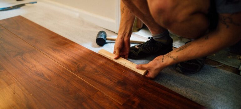 a man placing laminate flooring inside a home