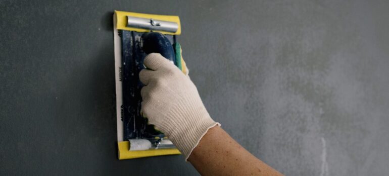 a man using sandpaper on a freshly remodeled wall