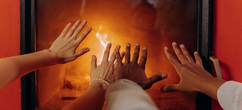 People warming their hands in front of a fireplace 