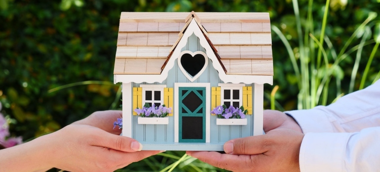 Couple holding a miniature wooden house 