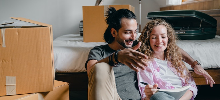 A happy couple reading a blog about things to pay attention to when hiring interstate movers 