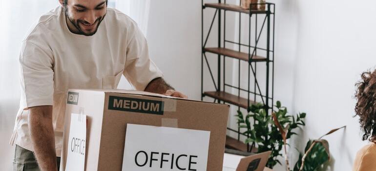 A man taking a box with office items while his girlfriend packs another