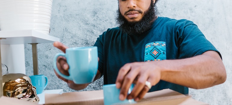 A professional packer packing coffee mugs