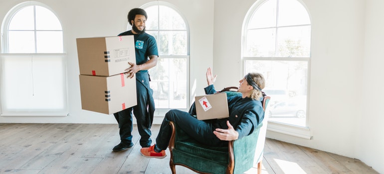 Two packers holding moving boxes and talking