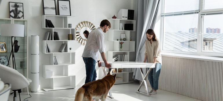 A man and a woman moving a table