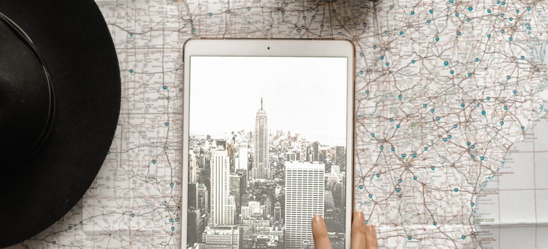 Flat lay photography of person touching silver ipad on world map