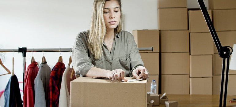 A woman taping a cardboard box