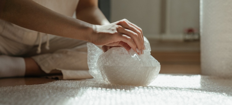 Person packing bath products in bubble wrap 