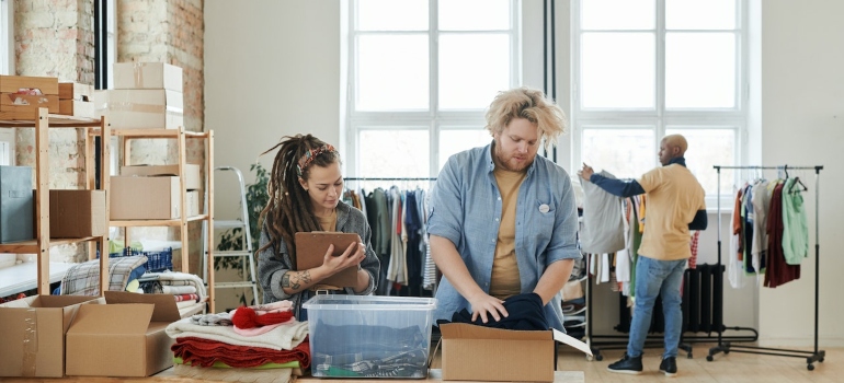 A man and a woman are storing clothes.