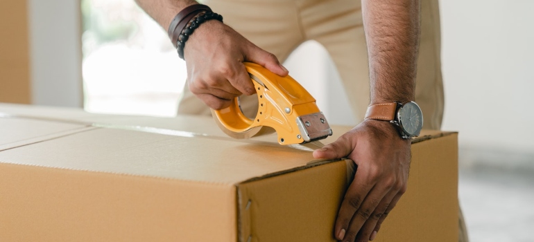 Person taping a box after he managed to pack framed pictures when moving