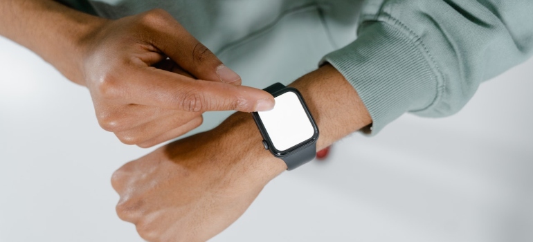 Person pointing at their watch, showing that it is time for packing your glass decorations when moving