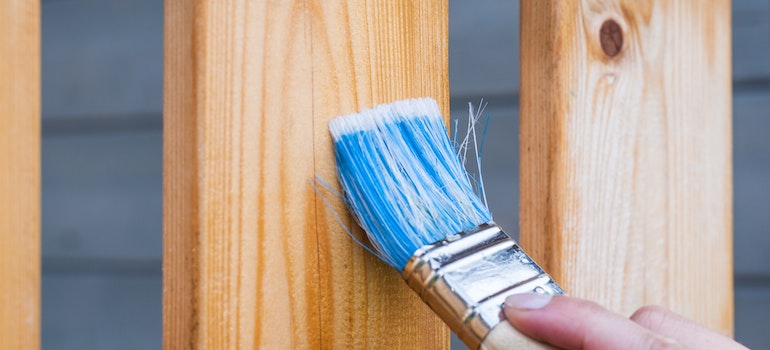 A painbrush being used before storing patio furniture