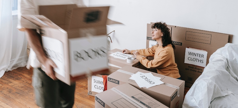 Two people packing boxes to relocate to Gaithersburg on a tight budget