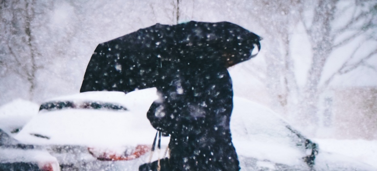 woman walking with umbrella and thinking about moving when it snows in DC